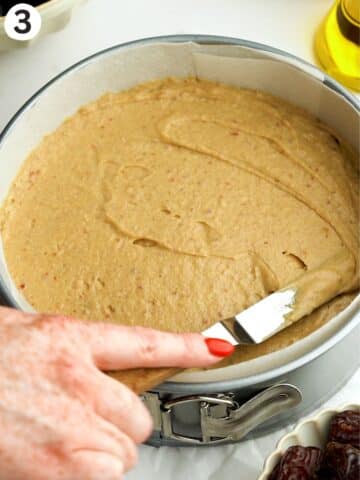 smoothing date cake batter into a pan with an offset spatula.