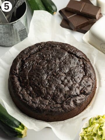 chocolate courgette cake cooling on a sheet of parchment paper.