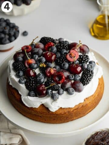 date sweetened cake topped with coconut cream, fresh berries, cherries and purple grapes.