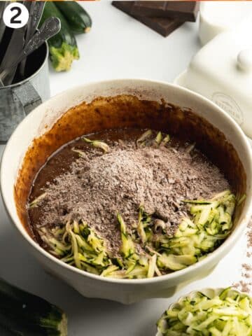 chocolate cake batter in a bowl with grated zucchini and dry ingredients before being folded through.