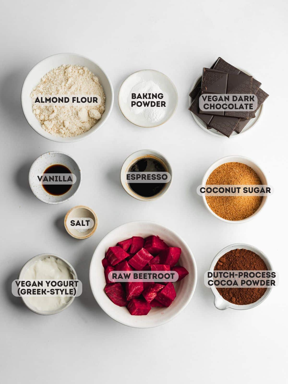 ingredients for beet brownies measured out in bowls on a light gray surface.