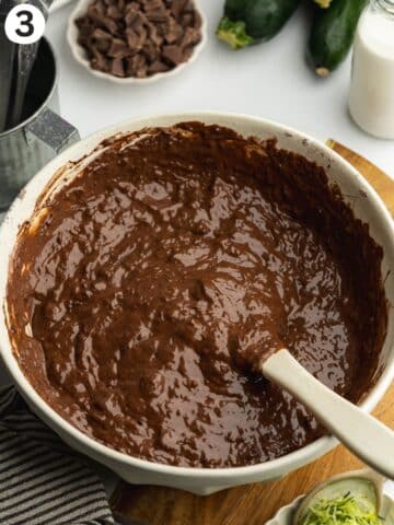 courgette chocolate muffin batter in a large ceramic bowl with a spatula.