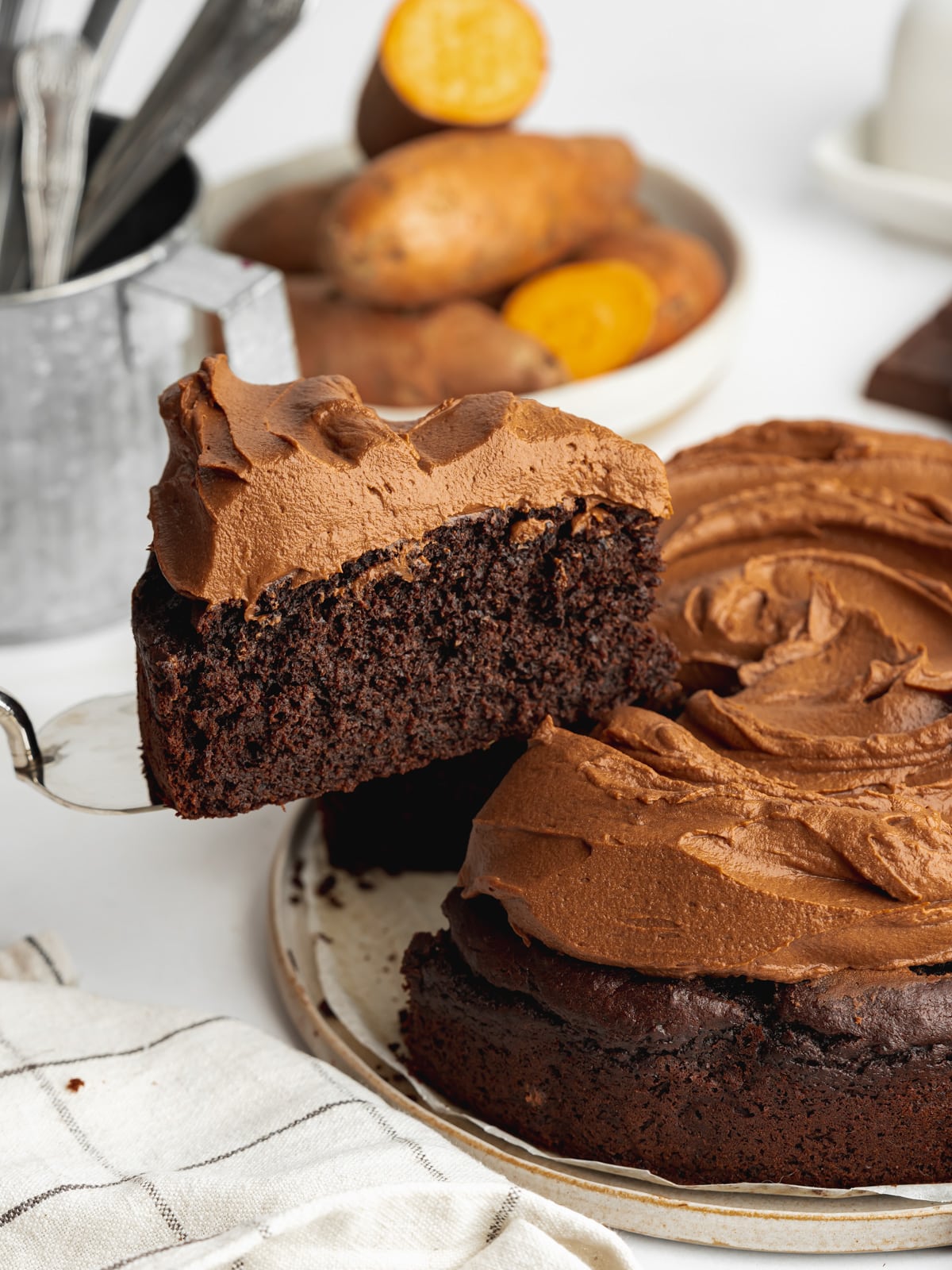 a slice of chocolate cake topped with sweet potato frosting before lifted away on a cake slice.