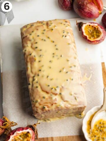 passion fruit loaf on a sheet of parchment with passion fruit glaze covering the top and sides.