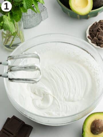 whipped coconut cream in a large glass mixing bowl with an electric mixer.