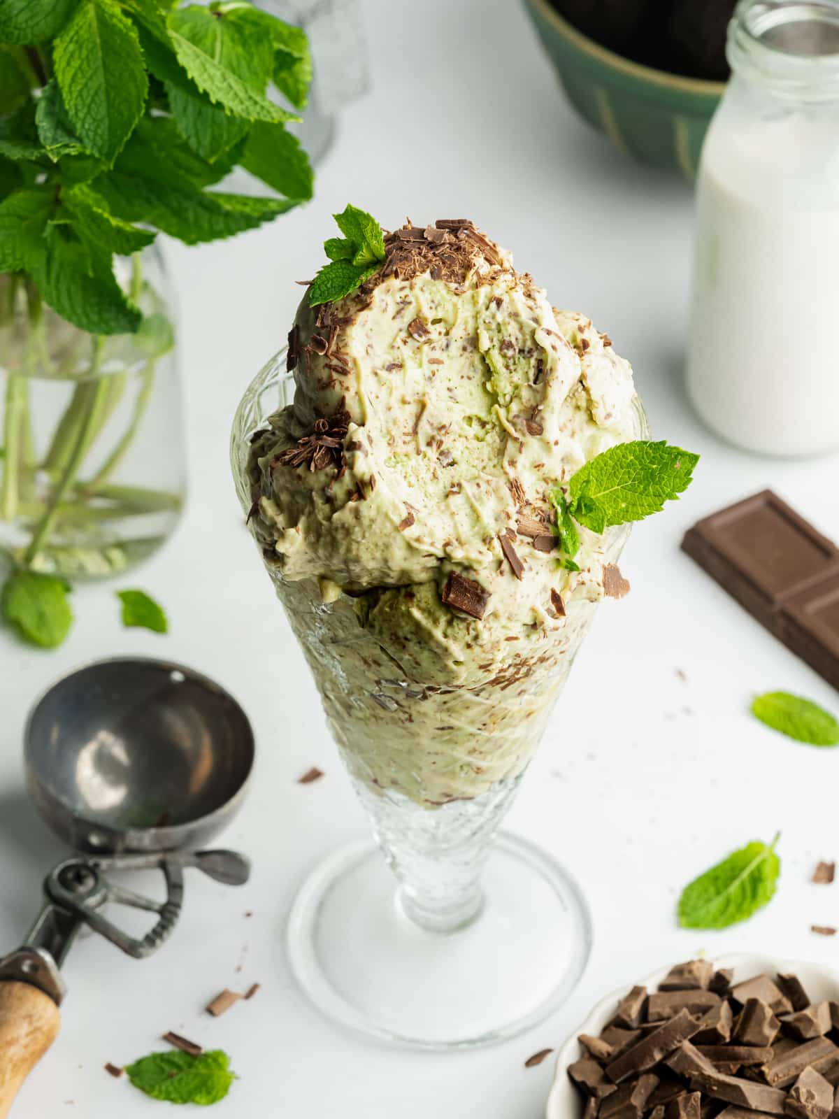 a serving glass filled with mint chocolate chip ice cream with a spoonful taken showing the creamy consistency.