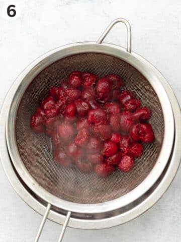 cherries in a fine-mesh sieve on top of a saucepan.