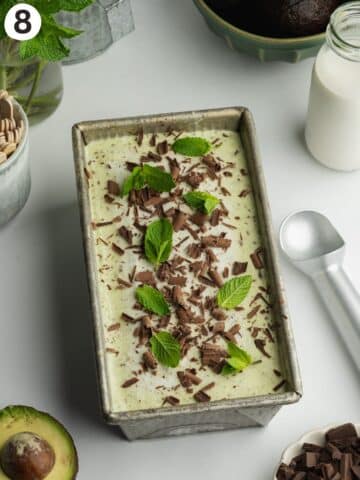mint choc chip ice cream in a loaf pan after freezing, and topped with more dark chocolate and fresh mint leaves.