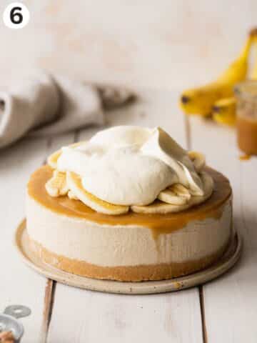 banana cheesecake on a ceramic plate topped with caramel, sliced fresh banana and vegan whipped cream.
