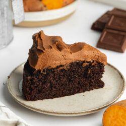 a slice of fluffy sweet potato chocolate cake with creamy sweet potato chocolate frosting on a ceramic plate.