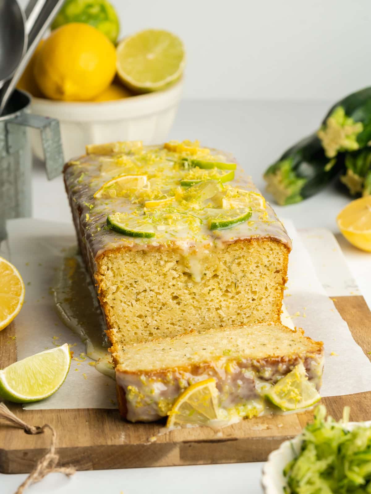 lemon and lime zucchini bread topped with fresh lime and lemon segments on a wooden board.
