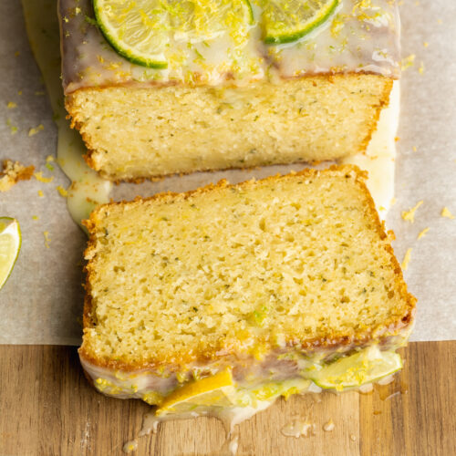 a slice of lemon zucchini bread with lime icing on a wooden cutting board.