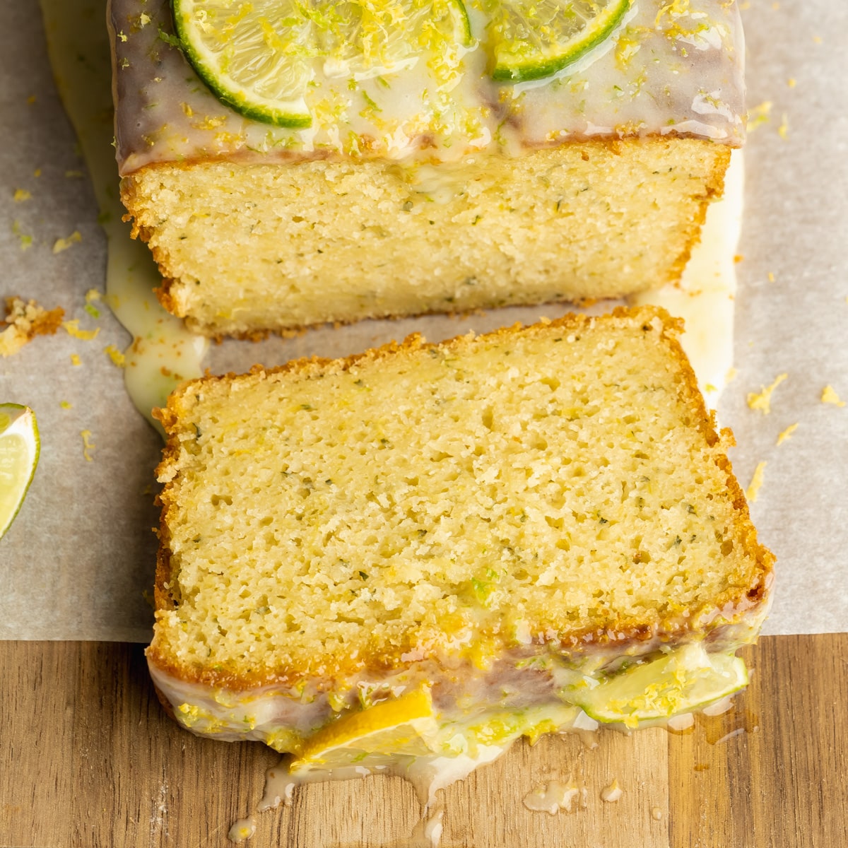 a slice of lemon zucchini bread with lime icing on a wooden cutting board.