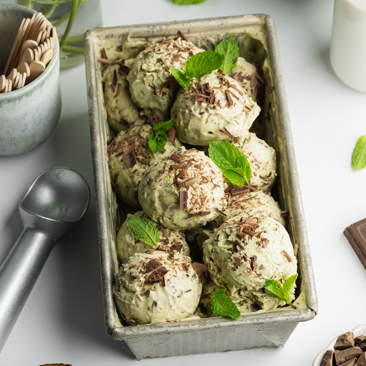a loaf pan filled with ice cream balls with fresh mint and dark chocolate shavings on top.