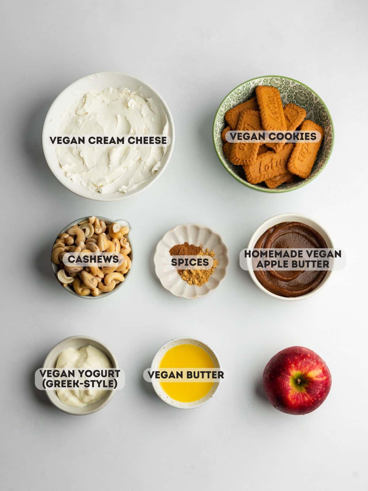 ingredients for apple butter cheesecake measured out in bowls on a gray surface.
