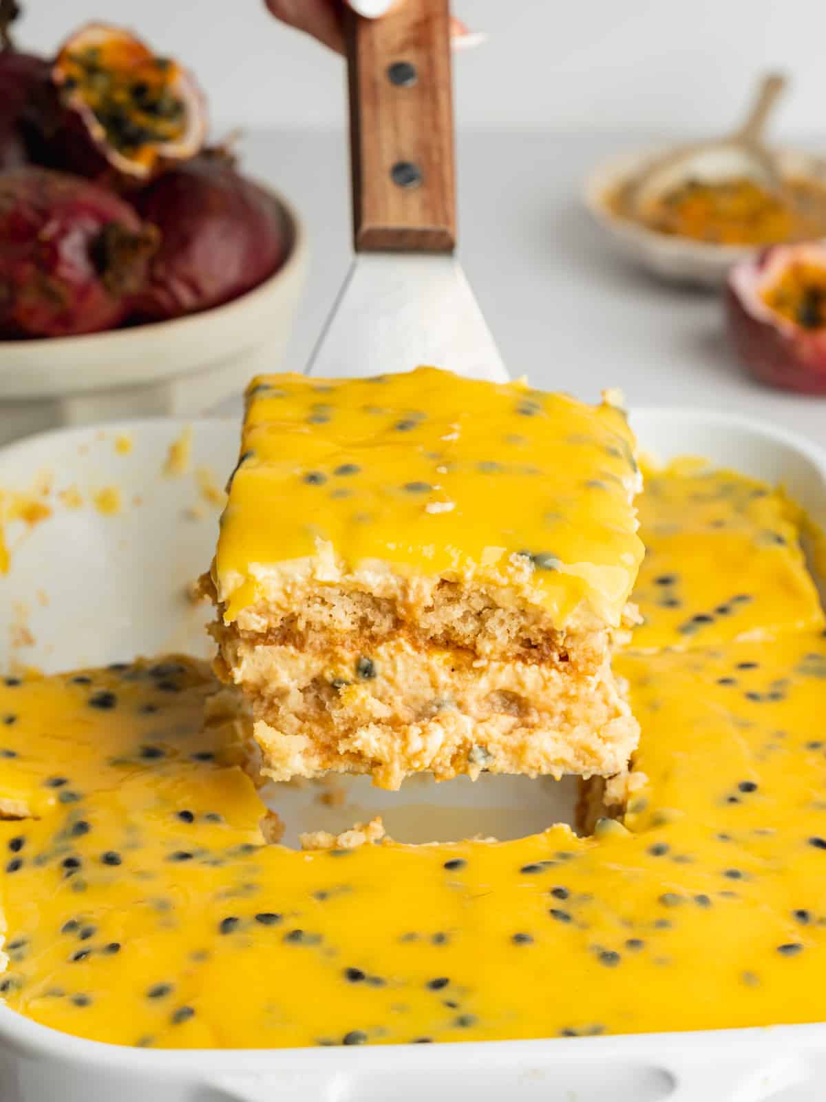 a cake slice holding up a piece of passion fruit tiramisu