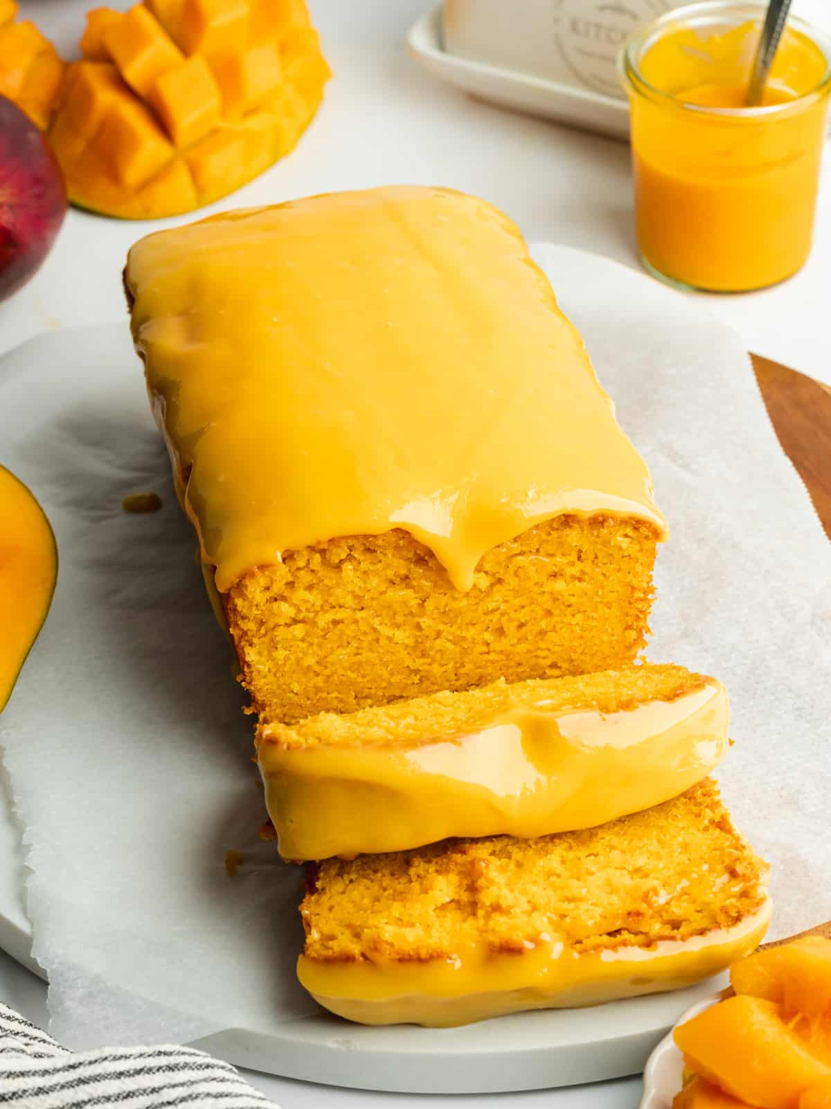 a mango loaf cake with mango icing and a few slices cut from it.