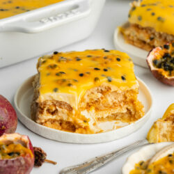 a slice of passionfruit tiramisu on a ceramic plate with a bite taken showing the creamy consistency.