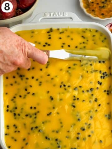 smoothing passion fruit curd on top of tiramisu with an offset spatula.