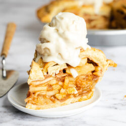 a slice of super tall apple pie with vanilla ice cream on top.