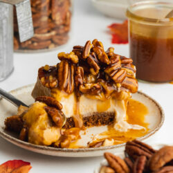 a slice of pecan pie cheesecake on a plate with a few spoonful taken.