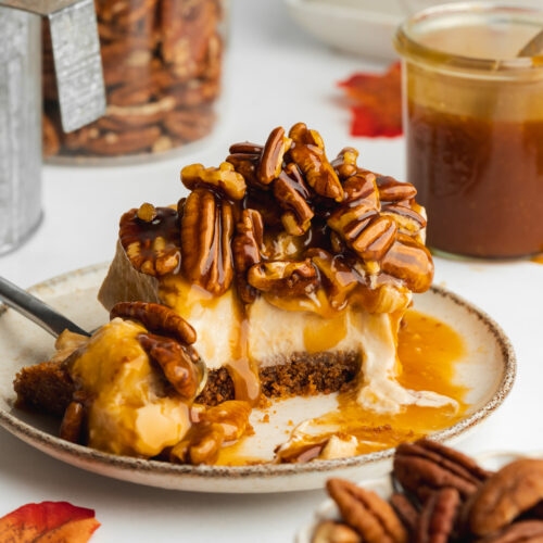 a slice of pecan pie cheesecake on a plate with a few spoonful taken.