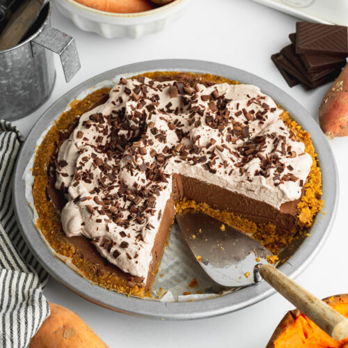 chocolate sweet potato pie topped with whipped cream with a couple of slices taken from it.