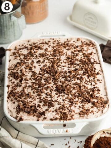 chocolate tres leches in a staub pan with chocolate shavings on top.