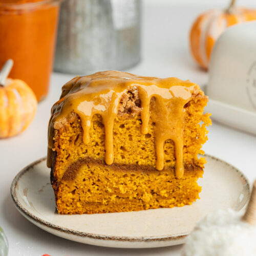 a slice of pumpkin coffee cake on a ceramic plate with pumpkin butter icing on top.