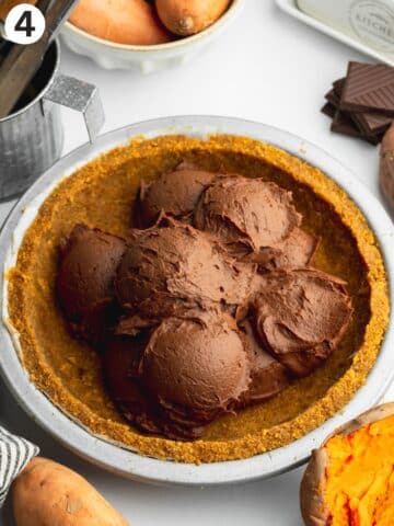 scoops of chocolate sweet potato filling in a pie crust before being smoothed out.