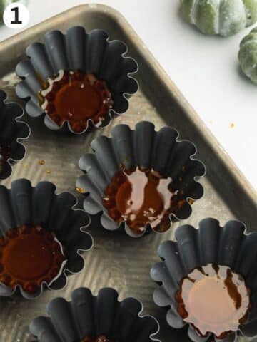 small flan molds with hardened caramel in the base.
