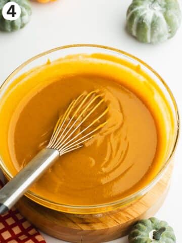smooth pumpkin flan mixture in a bowl with a whisk.