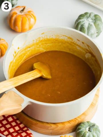 pumpkin custard filling in a saucepan with a rubber spatula.