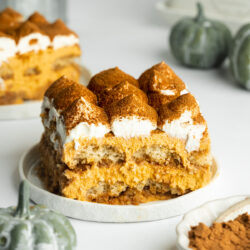 a slice of pumpkin tiramisu with whipped cream and pumpkin spices dusted on top.