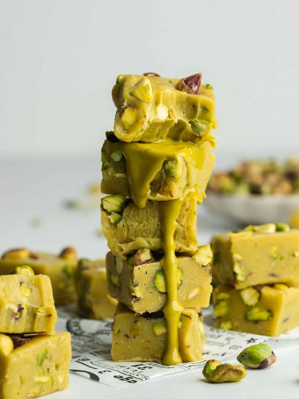 a stack of pistachio fudge squares with a bite taken out of the top piece showing the consistency.