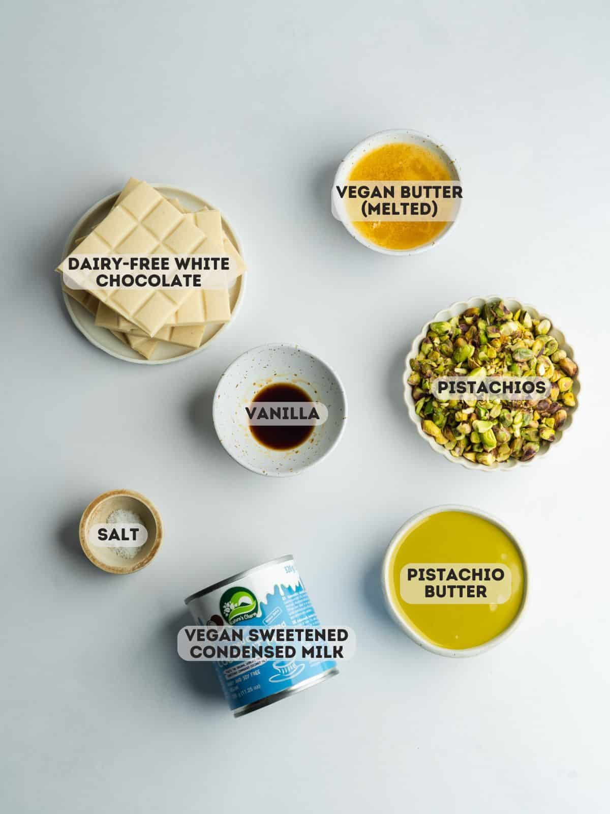 ingredients for pistachio fudge measured out in bowls on a gray surface.
