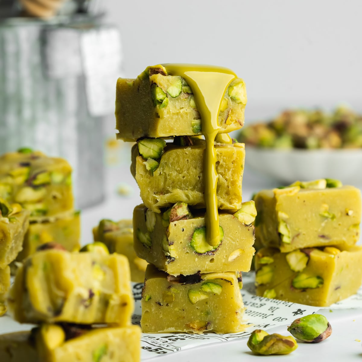 a stack of pistachio fudge pieces with pistachio butter pouring voer the edge.