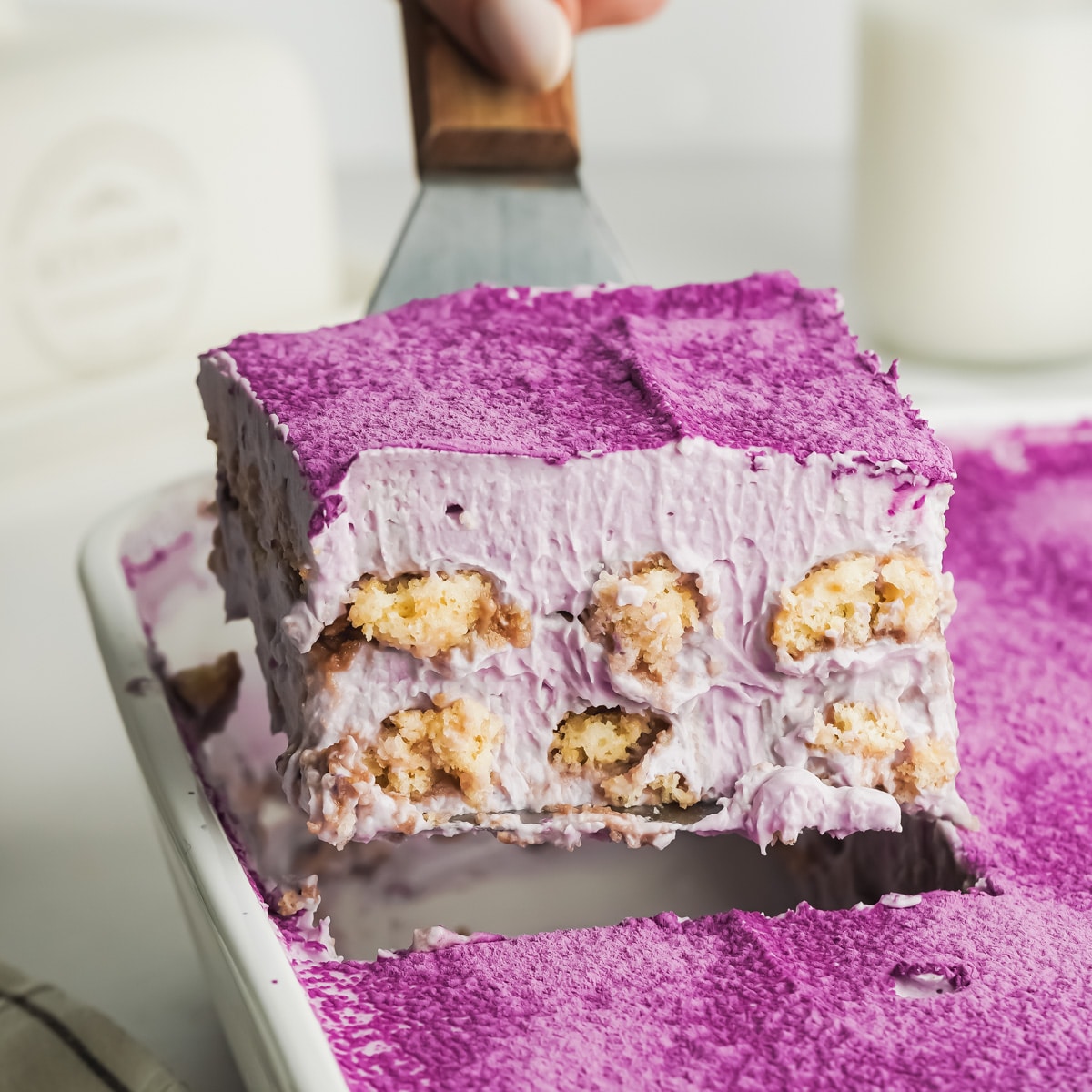 a slice of purple ube tiramisu being lifted up on a cake slice.