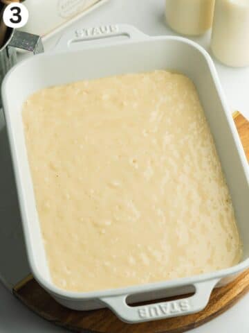 white staub ceramic dish with tres leches cake mixture before baking in the oven.