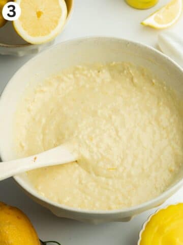 lemon cake batter in a ceramic bowl with a rubber spatula.