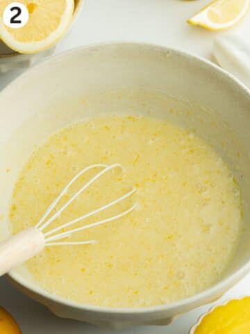 wet ingredients for lemon tres leches in a mixing bowl with a whisk.