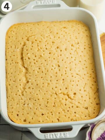 tres leches cake in a rectangular staub pan with holes poked into it before soaking in the milk mixture.