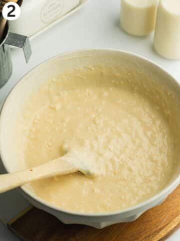 tres leches cake batter in a ceramic bowl with a spatula.