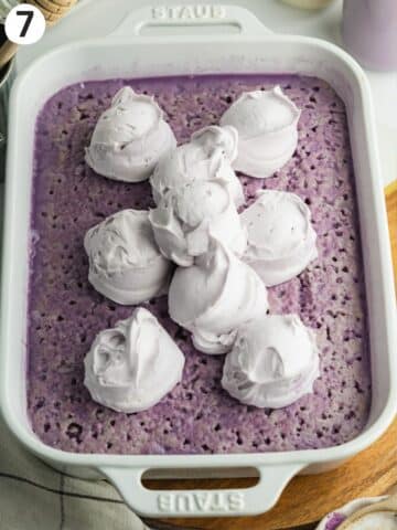 ube tres leches with scoops of ube whipped cream on top.