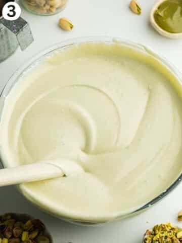 pistachio ice cream mixture folded with a spatula in a large mixing bowl.