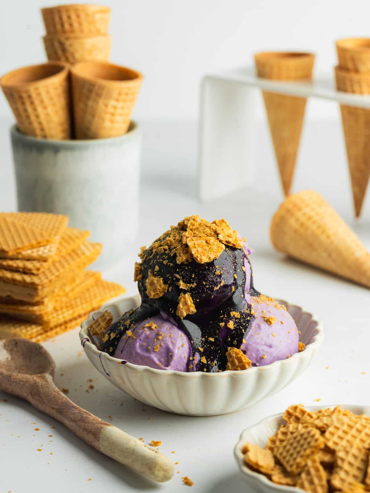 a small bowl with scoope of ube ice cream topped with ube condensed milk and crushed wafers.