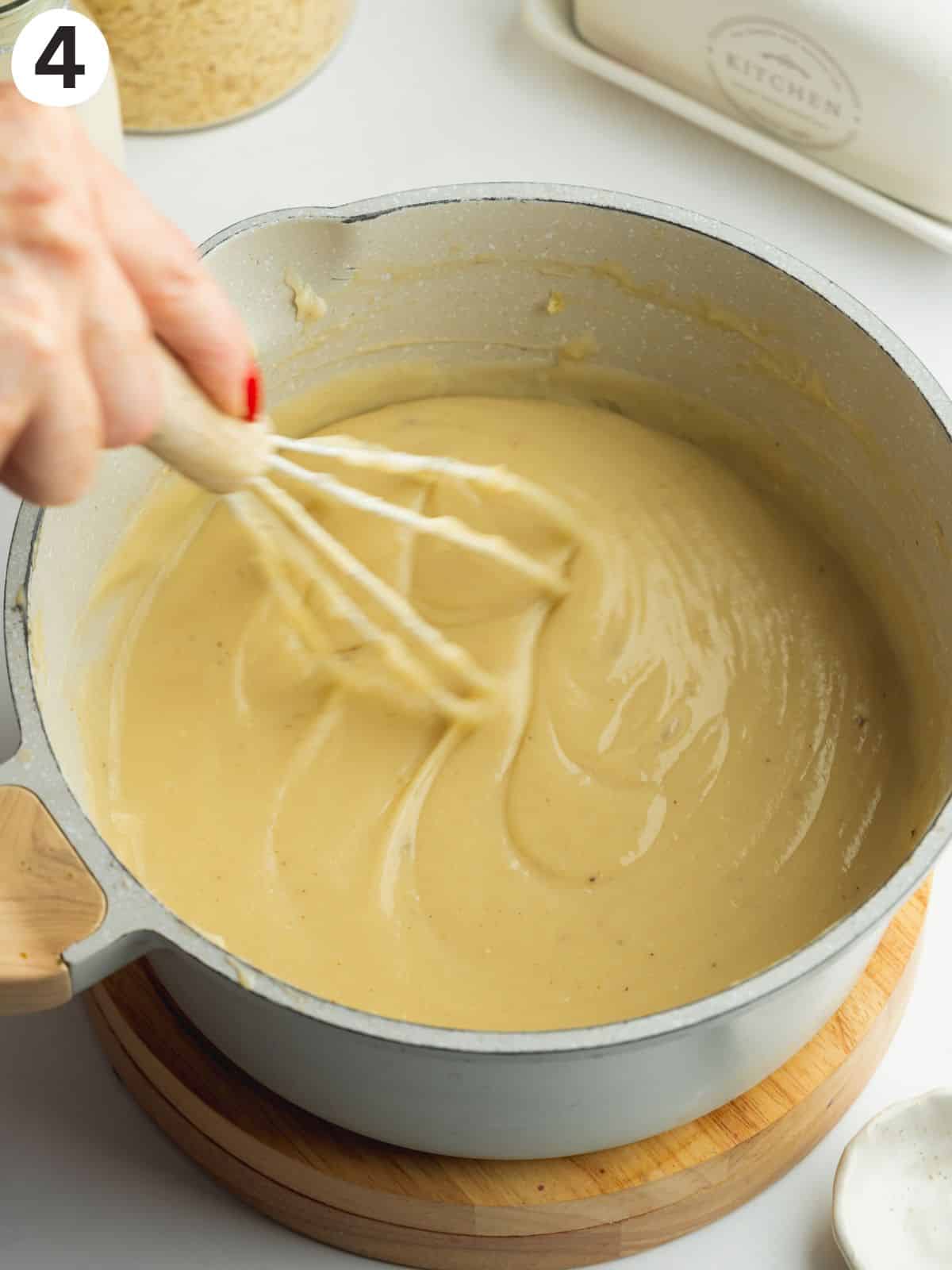 thickened vegan bechamel in a saucepan with a whisk.