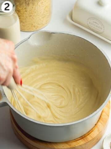 a vegan roux being whisked in a saucepan with some soy milk.