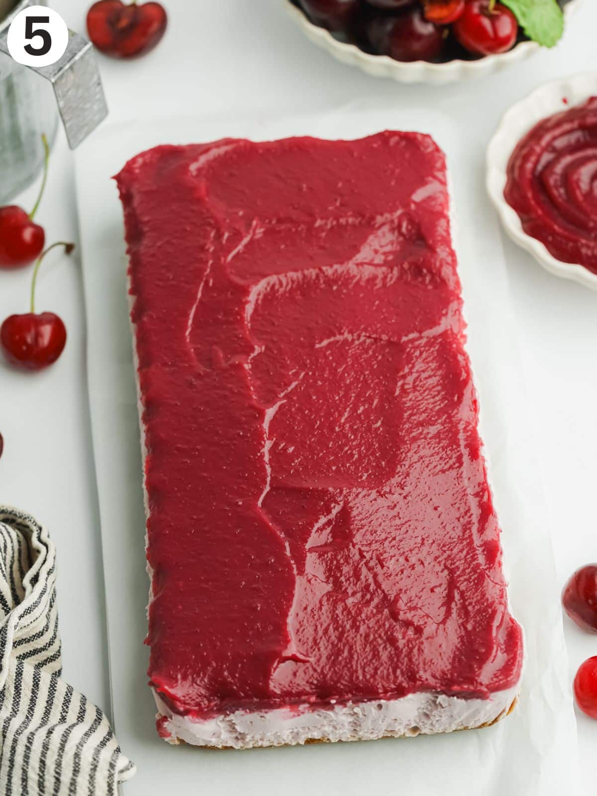 cherry cheesecake topped with cherry curd before slicing.