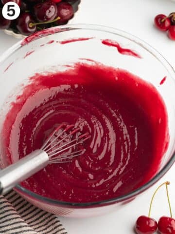 smooth cherry curd in a glass bowl with a sieve.